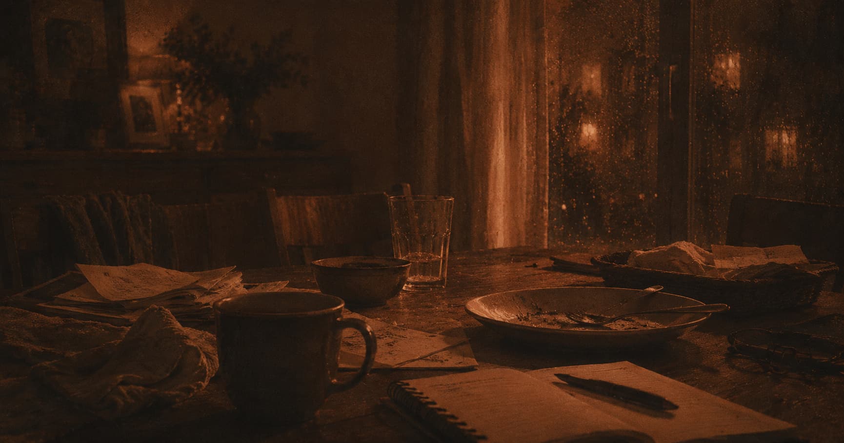 Table de fin de repas avec tasse et papiers, dans une lumière chaude tamisée